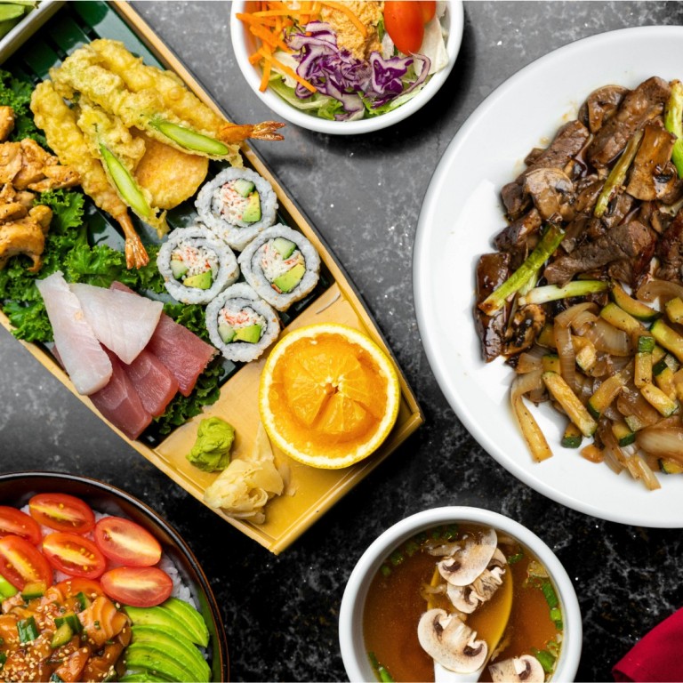 Benihana lunch spread featuring fresh sushi rolls, sashimi, hibachi steak, mushroom soup, and Asian salad.
