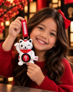 A child girl smiling and holding up a Benihana Lucky cat bag charm